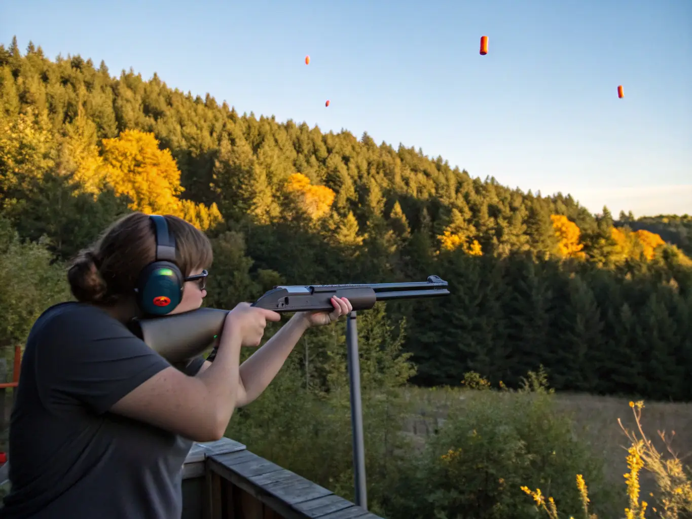 A high-definition image of a ball trap shooting range with a shooter in action, clay targets in mid-air, and safety equipment visible. The scene captures the dynamic nature of the sport and the club's commitment to safety.